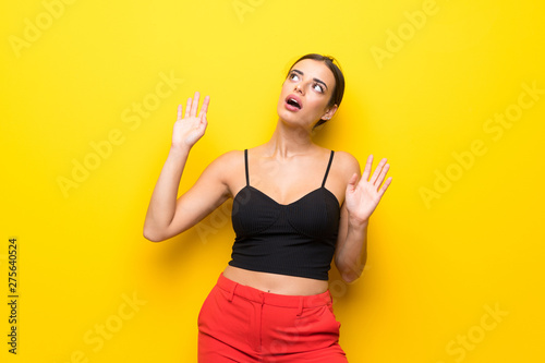 Young woman over isolated yellow background nervous and scared