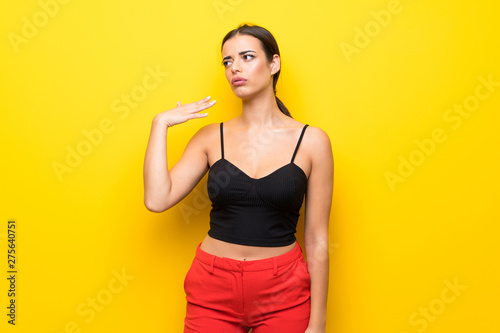 Young woman over isolated yellow background with tired and sick expression