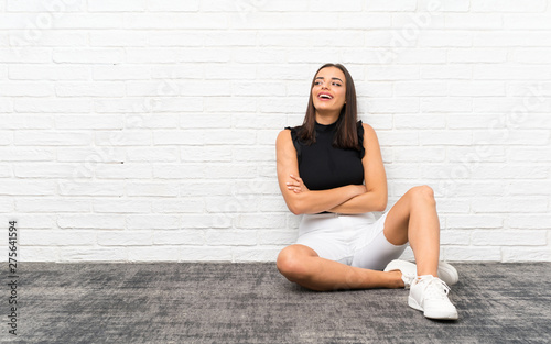 Pretty young woman sitting on the floor happy and smiling