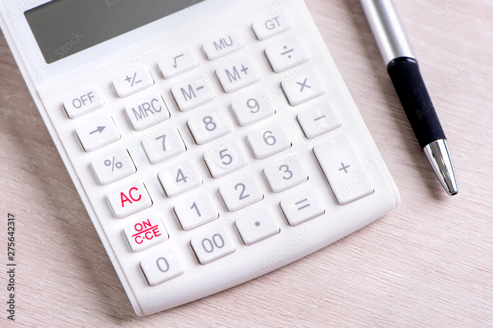 White calculator and pen on bright wooden table, analytics and statistics of financial profit, investment risk concept, copy space, macro, close up White calculator and pen on bright wooden table, analytics and statistics of financial profit, investment risk concept, copy space, macro, close up
