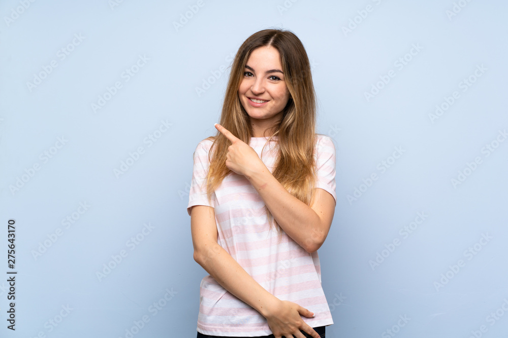 Young woman over isolated blue background pointing to the side to present a product Young woman over isolated blue background pointing to the side to present a product
