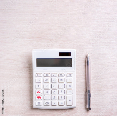 White calculator and pen on bright wooden table, analytics and statistics of financial profit, investment risk concept, copy space, top view flat lay