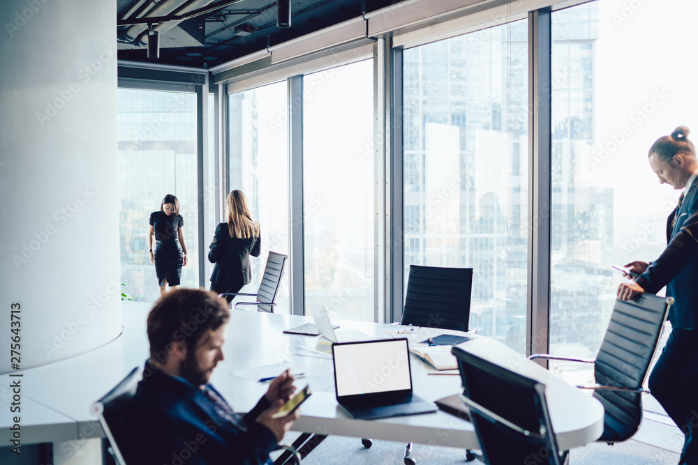Group of business people ignoring live communication using their cellphones in office interior with big windows. Four employees standing separate. Millennial problem, antisocial concept Group of business people ignoring live communication using their cellphones in office interior with big windows. Four employees standing separate. Millennial problem, antisocial concept