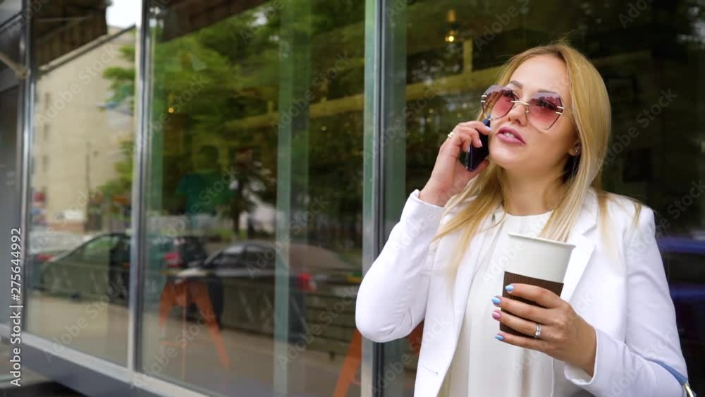 beautiful blonde woman talking on mobile phone holding coffee cup on the street beautiful blonde woman talking on mobile phone holding coffee cup on the street