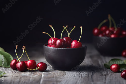 Ripe red cherries in a bowl and next to it photo