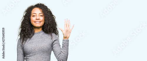 Young beautiful girl with curly hair showing and pointing up with fingers number five while smiling confident and happy. © Krakenimages.com