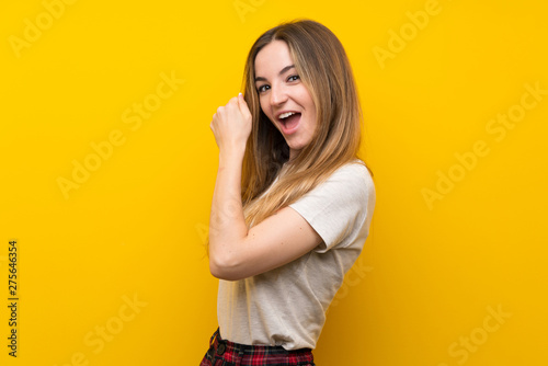 Young woman over isolated yellow wall celebrating a victory © luismolinero