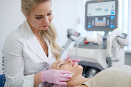 Woman getting treatment with aesthetic dermatology device photo