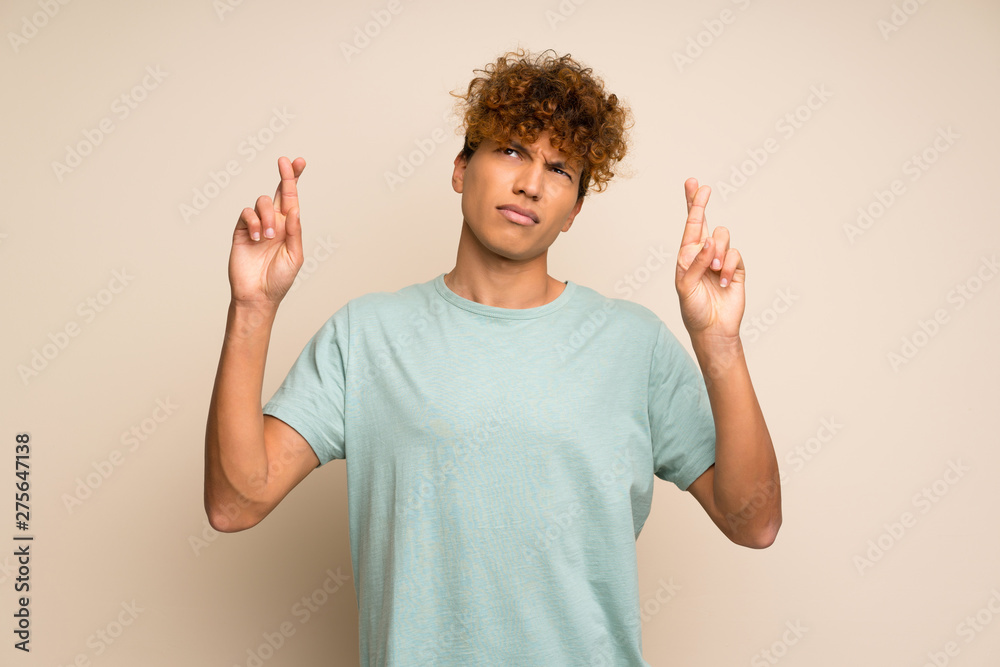African american man with green shirt with fingers crossing and wishing the best African american man with green shirt with fingers crossing and wishing the best