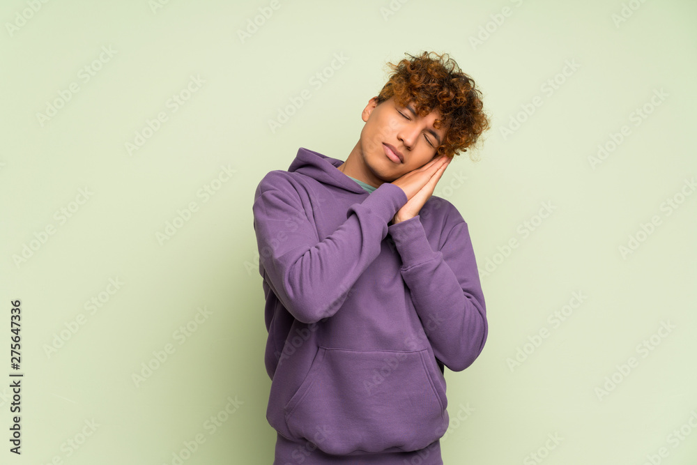 Young african american man over isolated green wall making sleep gesture in dorable expression Young african american man over isolated green wall making sleep gesture in dorable expression