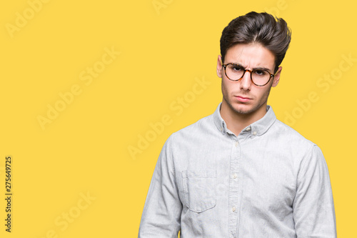 Young handsome man wearing glasses over isolated background skeptic and nervous, frowning upset because of problem. Negative person.