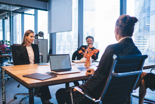 Intelligent business people dressed in formal wear sitting at meeting table and discussing information about startup project during working process in company office, concept of entrepreneurship