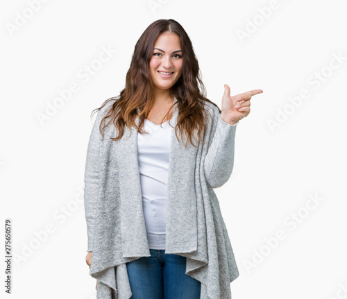 Beautiful plus size young woman wearing winter jacket over isolated background with a big smile on face, pointing with hand and finger to the side looking at the camera.