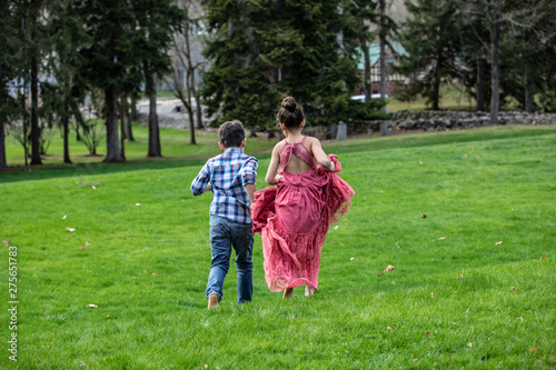 BOY & GIRL RUNNING ON GRASSY FIELD