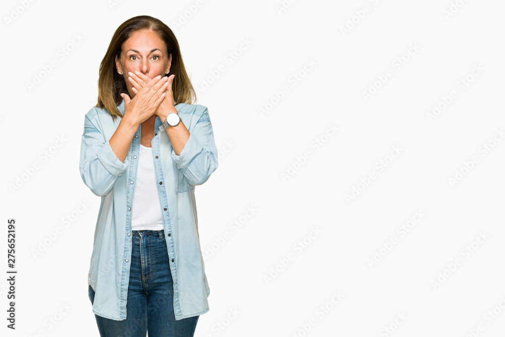 Middle age adult woman wearing casual denim shirt over isolated background shocked covering mouth with hands for mistake. Secret concept. Middle age adult woman wearing casual denim shirt over isolated background shocked covering mouth with hands for mistake. Secret concept.