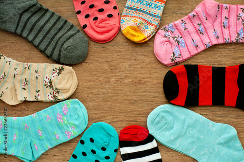 Colorful socks on wooden background. Knitted multicolored socks folded in the form of the sun. Clothing in the form of socks. View from above.