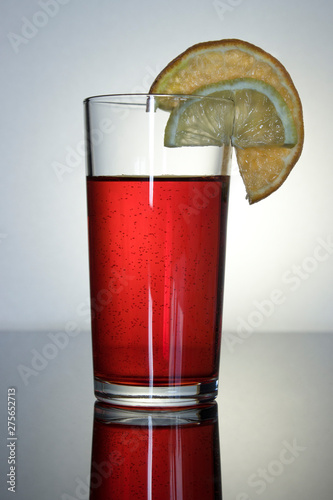 pink drink in a glass glass Cup with reflection, a slice of lemon and orange