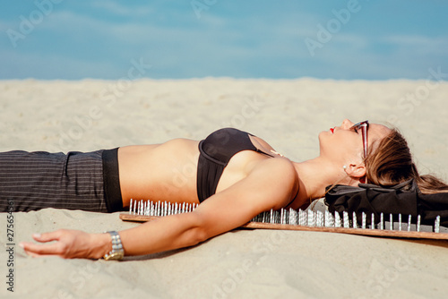  extreme yoga relaxation and self-development - beautiful office woman laying nacked back on the board with nails in desert outdoor