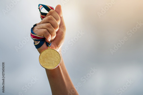 Hand holding gold medal on sky background photo
