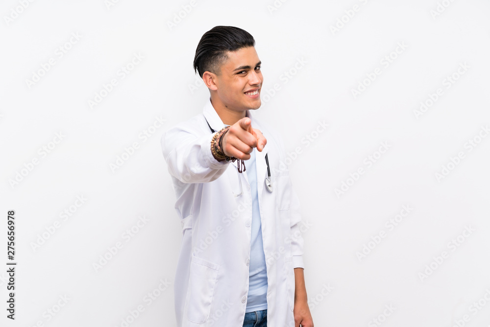 Young doctor man over isolated white wall points finger at you with a confident expression Young doctor man over isolated white wall points finger at you with a confident expression