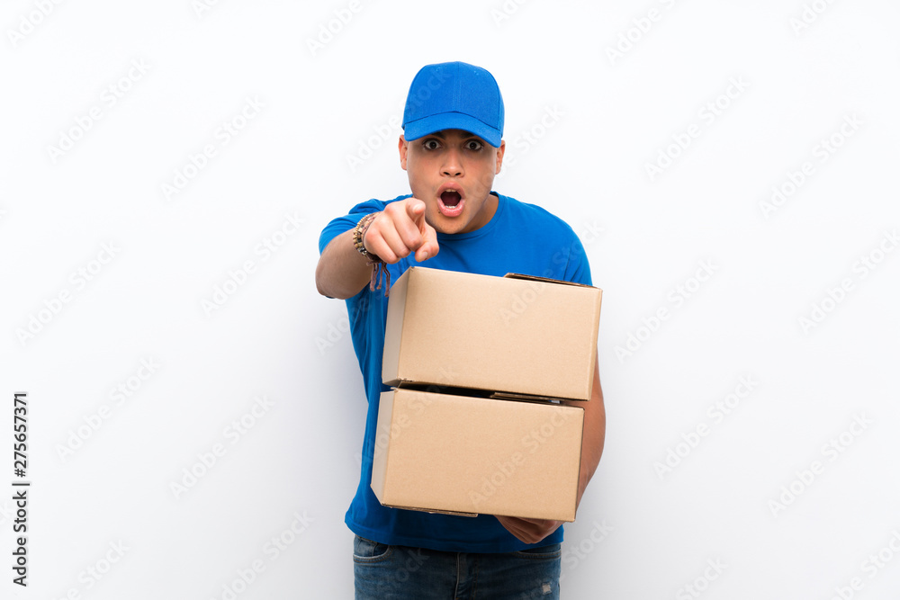 Delivery man over isolated white wall surprised and pointing front Delivery man over isolated white wall surprised and pointing front