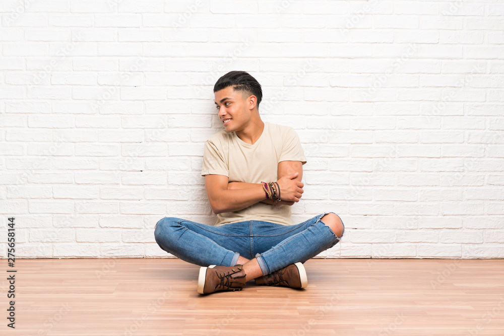 Young man sitting on the floor looking to the side Young man sitting on the floor looking to the side