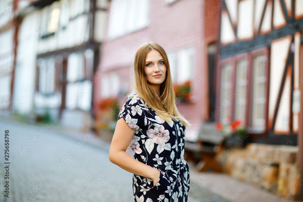 Beautiful young woman with long hairs in summer dress going for a walk in German city. Happy girl enjoying walking in cute small fachwerk town with old houses in Germany. Beautiful young woman with long hairs in summer dress going for a walk in German city. Happy girl enjoying walking in cute small fachwerk town with old houses in Germany.