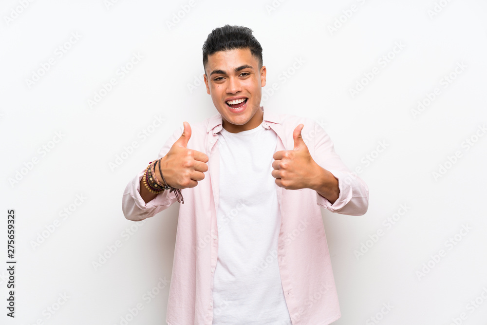 Young man over isolated white wall giving a thumbs up gesture Young man over isolated white wall giving a thumbs up gesture