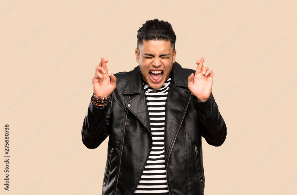 Naklejka premium Young man with fingers crossing over isolated background