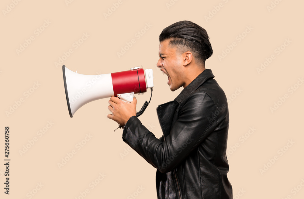 Young man shouting through a megaphone over isolated background Young man shouting through a megaphone over isolated background