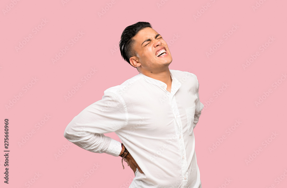 Young man suffering from backache for having made an effort on colorful background Young man suffering from backache for having made an effort on colorful background