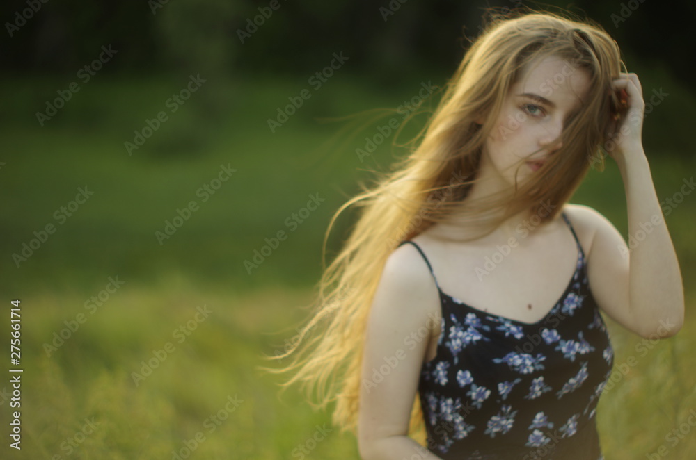  beautiful young blonde with long flowing hair on a blurred background of summer greenery