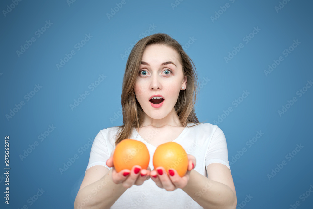 Young beautiful girl model with oranges on blue background, girl shows oranges on camera Young beautiful girl model with oranges on blue background, girl shows oranges on camera