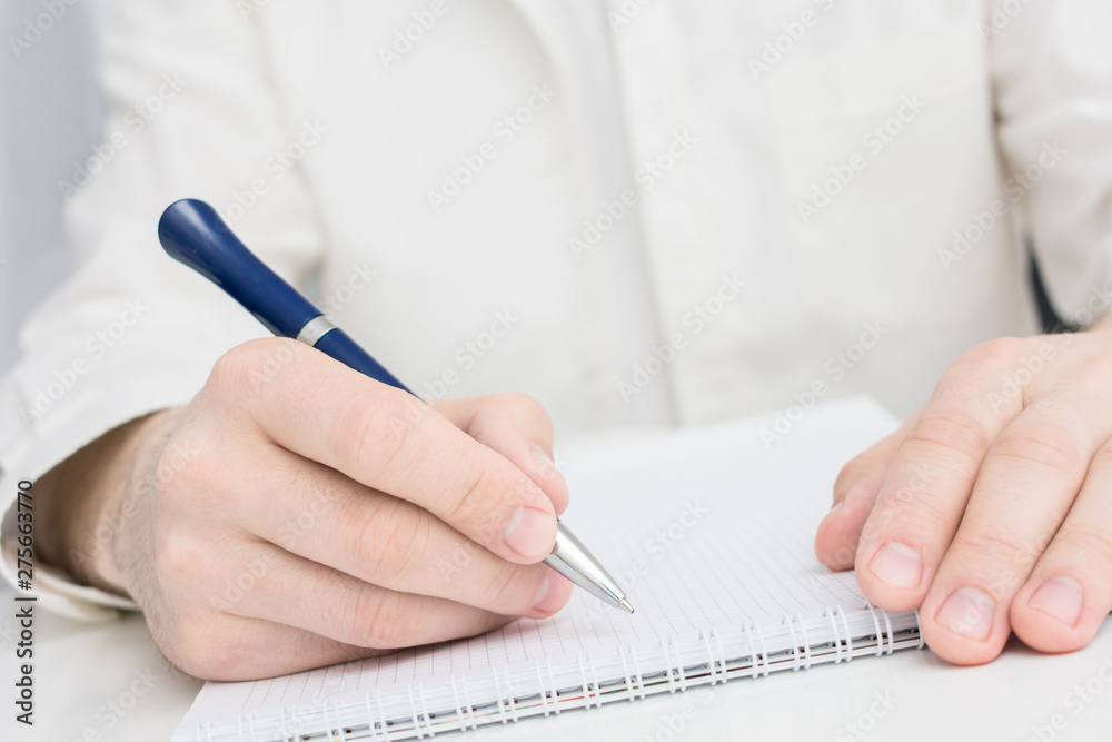 Men's hands, man writes something in a notebook, makes notes Men's hands, man writes something in a notebook, makes notes