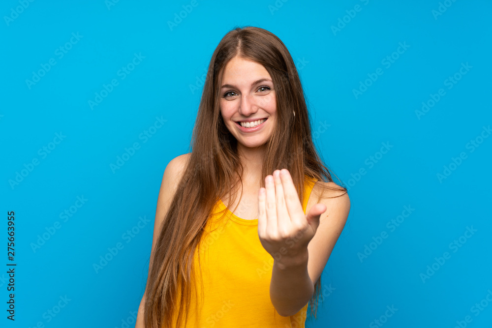 Young woman with long hair over isolated blue wall inviting to come with hand. Happy that you came Young woman with long hair over isolated blue wall inviting to come with hand. Happy that you came