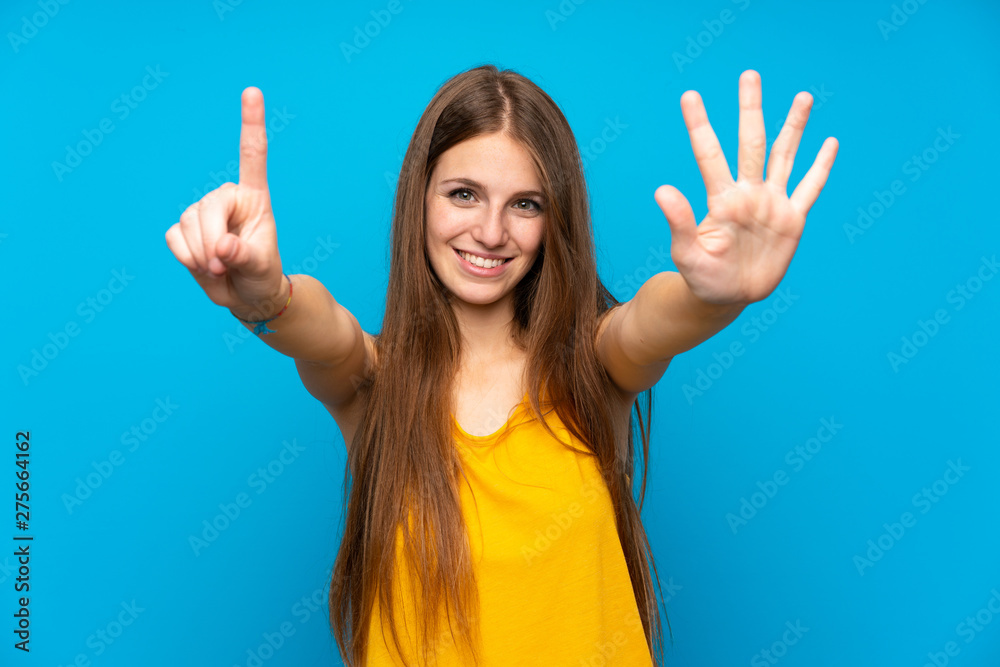 Young woman with long hair over isolated blue wall counting six with fingers