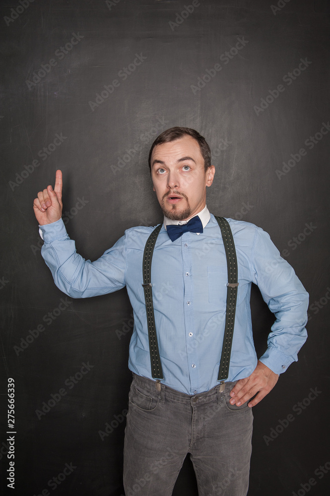 Handsome teacher showing up on something by finger on blackboard Handsome teacher showing up on something by finger on blackboard