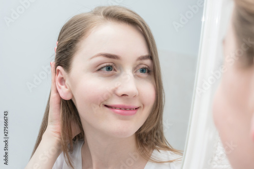 Reflection in the mirror of a smiling young girl, looks in the mirror, close up