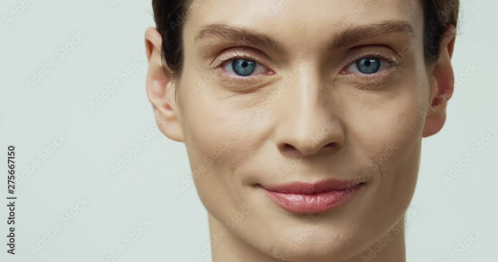 Portrait of the charming pretty young Caucasian woman with blue eyes turning face to the camera and smiling straight to the camera. Portrait of the charming pretty young Caucasian woman with blue eyes turning face to the camera and smiling straight to the camera.