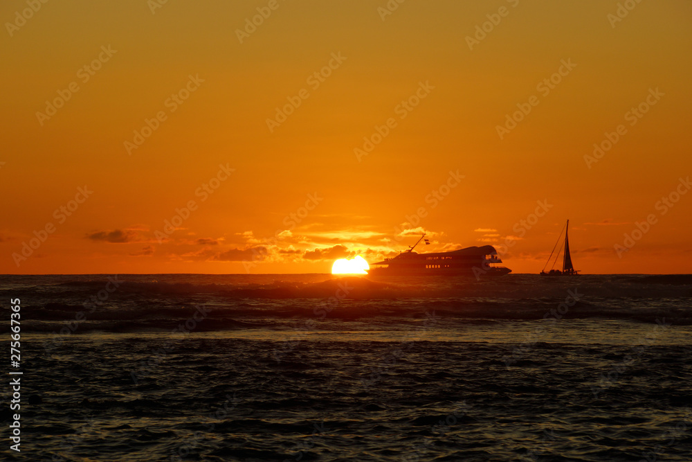 Sunset over the ocean with light reflecting on ocean waves moving with boats on the water in the distance