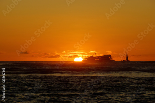 Sunset over the ocean with light reflecting on ocean waves moving with boats on the water in the distance © Eric BVD
