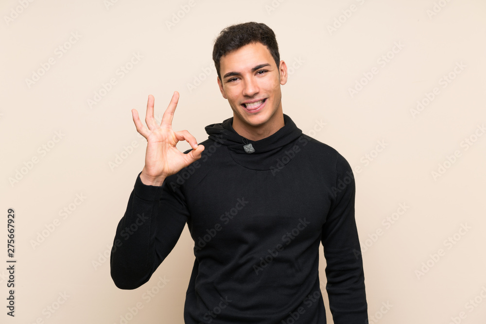 Handsome man over isolated background showing an ok sign with fingers