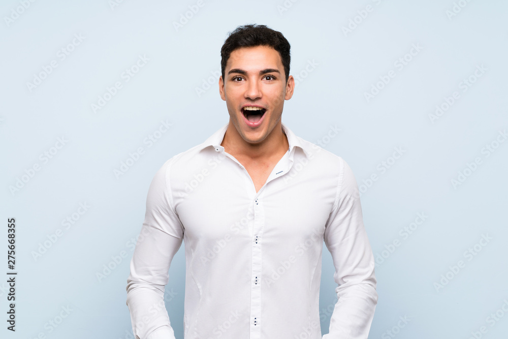 Handsome man over blue wall with surprise facial expression Handsome man over blue wall with surprise facial expression