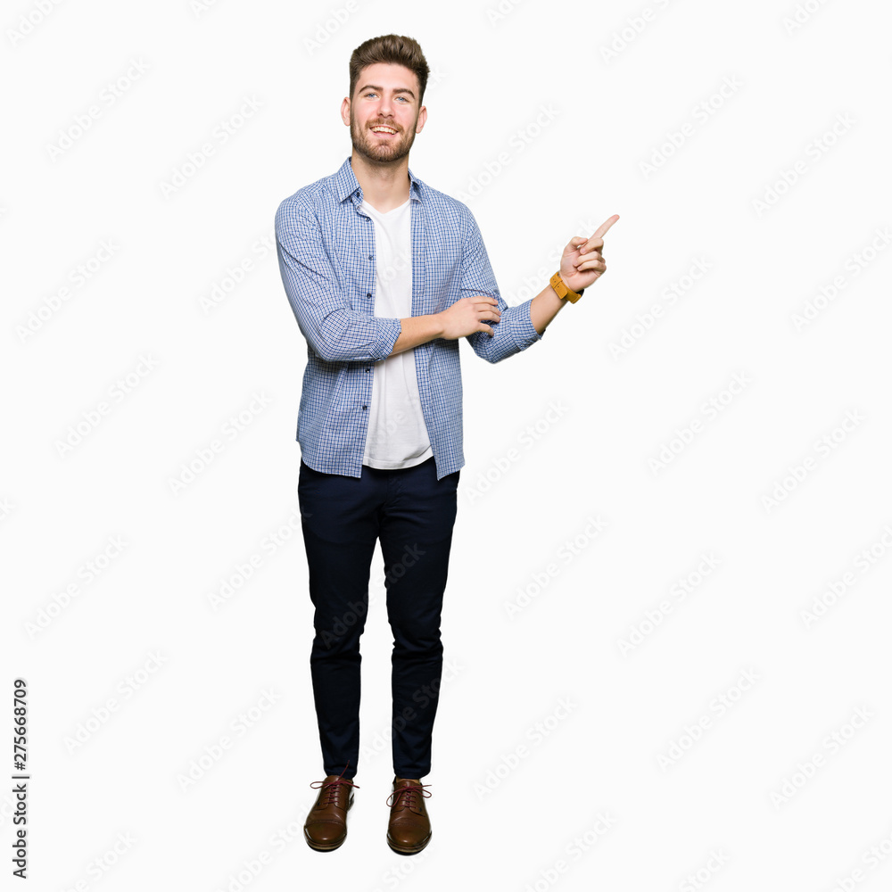 Young handsome blond man wearing casual shirt with a big smile on face, pointing with hand and finger to the side looking at the camera. Young handsome blond man wearing casual shirt with a big smile on face, pointing with hand and finger to the side looking at the camera.