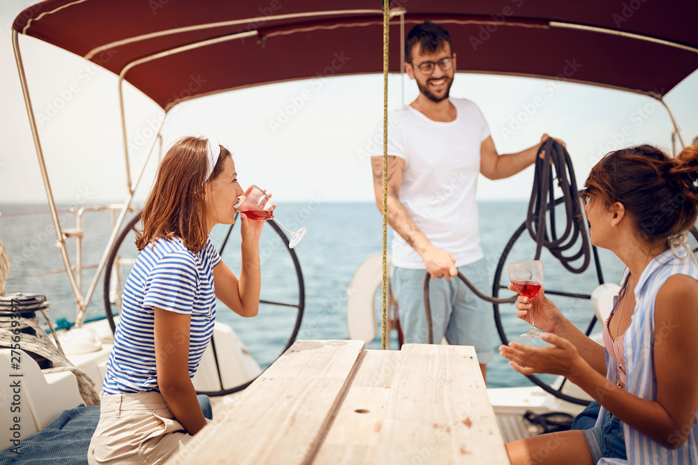 Fototapeta premium People sitting on sailboat deck and having fun. Vacation, travel, sea, friendship and people concept..