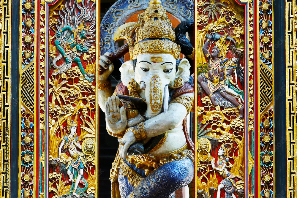 Obraz premium statue of ganesh …god of prosperity and success with carved door in balinese temple 