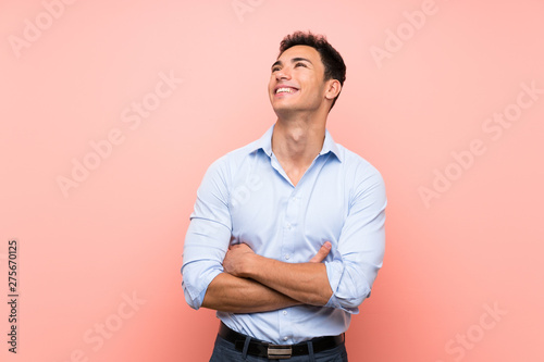 Handsome man over pink background looking up while smiling
