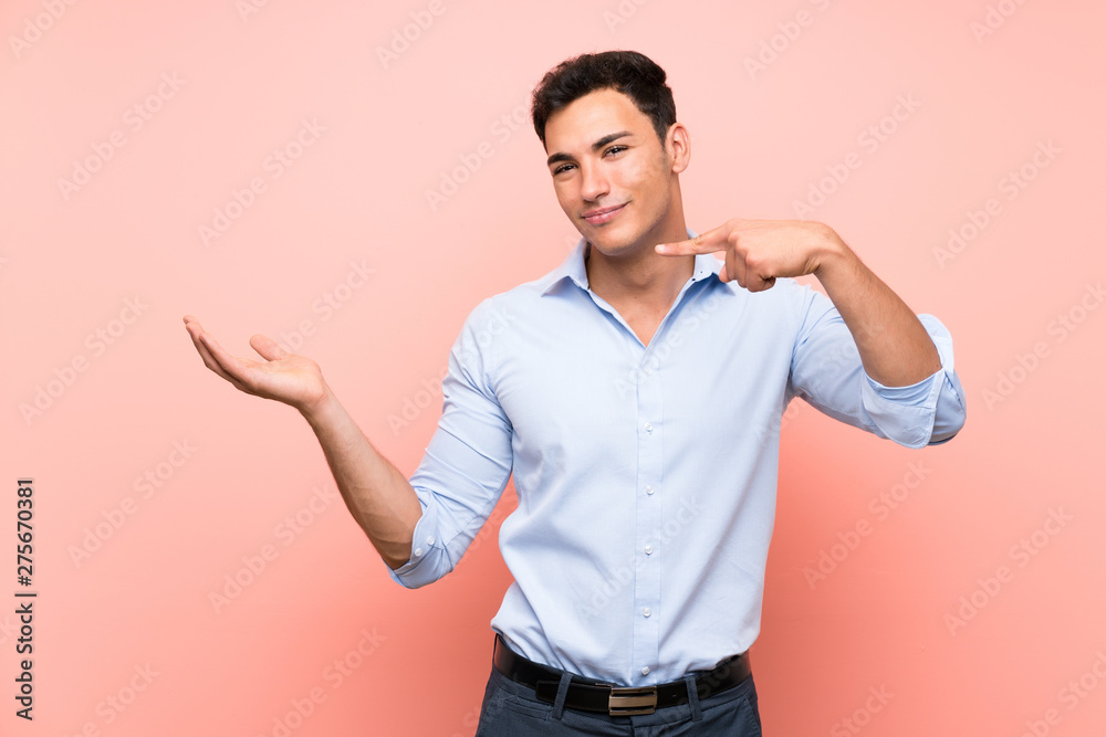 Handsome man over pink background holding copyspace imaginary on the palm to insert an ad Handsome man over pink background holding copyspace imaginary on the palm to insert an ad