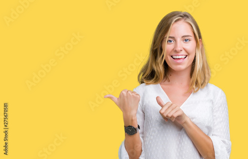 Beautiful young elegant woman over isolated background Pointing to the back behind with hand and thumbs up, smiling confident photo