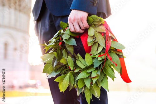 Plakat w ramie Giovane laureato con corona d'alloro verde e nastro rosso tenuto in mano. Cerimonia di laurea.